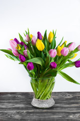 Glass vase with bouquet of beautiful multicolor spring tulips on white background