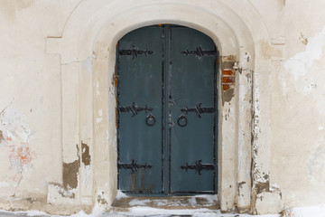 Fototapeta na wymiar Old metal door on a white stone wall