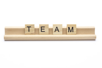 Word ''team'' on scrabble wooden letters on a rack, isolated on white background. Lower case letters.