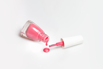 Spilled pink nail polish and brush on white background. Fashion woman still life. Pop female things