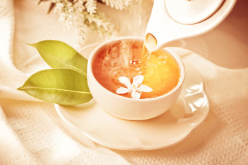 Close up pouring hot jasmine tea in a white tea cup ,  Tea ceremony time concept , vintage color tone