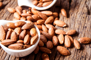 close up Peeled almonds nut  in small white cup on wooden  background