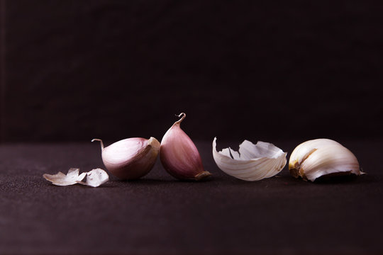  a still life arrangement of Three whole garlic bulbs grouped on black stone plate