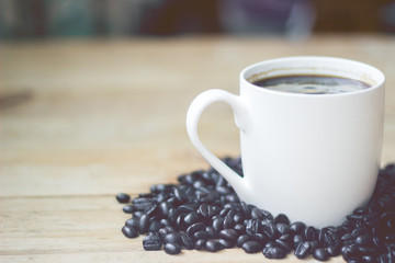 white cup coffee and coffee bean on wood vintage tone