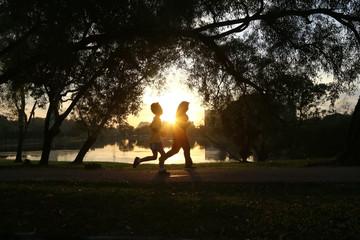 Silhouette of people jogging in park during morning sunrise