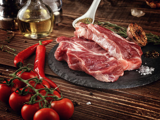 Raw pork neck steak on a stone plate.