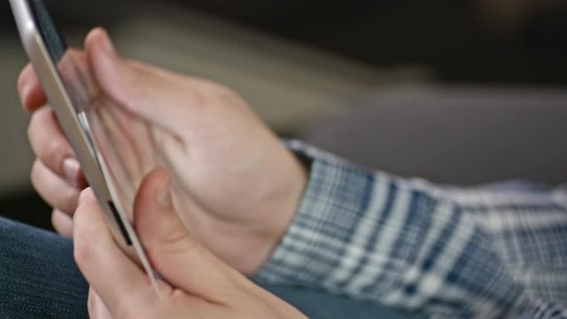 profile close-up of man's hands uses a digital tablet and credit card at home