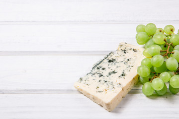 Slice of blue cheese and grapes on a white background.