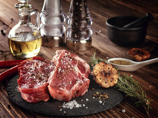 Raw pork neck steak on a stone plate.