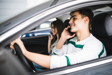 Portrait of a young couple speal phone and driving together, as seen through the windshield