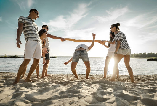 Friends funny game on the beach under sunset sunlight.