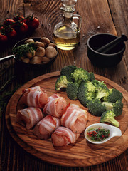 Raw rolls of turkey bacon on a wooden plate.