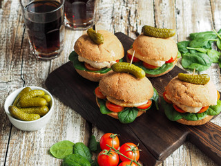Fototapeta na wymiar Homemade sandwiches with grilled chicken, tomatoes and spinach on a rustic bun on old wood background 