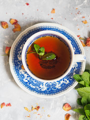 Herbal tea with mint in a blue cup on a saucer on a gray background
