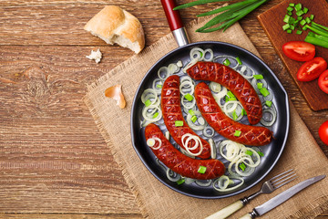 Fried sausages in a pan with onions.