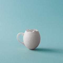 Egg shell coffee cup on pastel blue background. Minimal Easter concept.