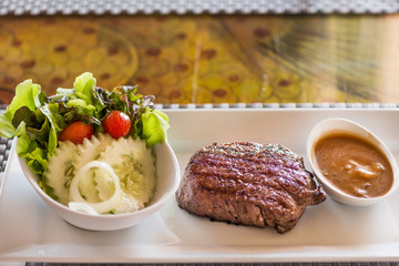 A steak with vegetable salad ,serve with mushroom sauce.