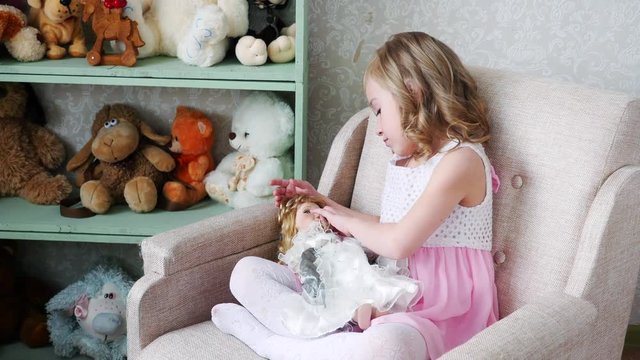 girl sitting on chair and playing with a doll