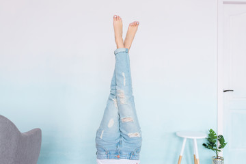 Women’s legs in blue jeans with white pedicure on a blue and white gradient background. Indoors
