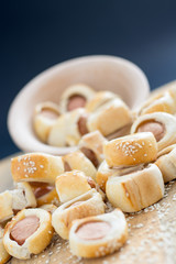  Sausages rolled in croissant dough baked cooling on metal rack.