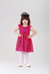 beautiful little girl in pink Princess dress with crown on gray 