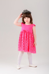 beautiful little girl in pink Princess dress with crown on gray 