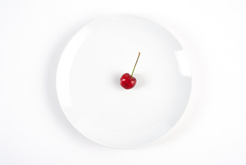 Single cherry on white plate isolated on white background