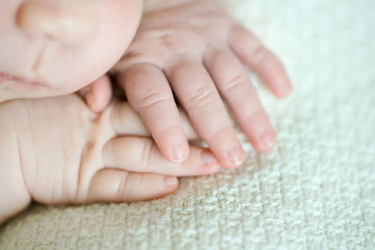 Hands cute sleeping newborn girl, close-up.