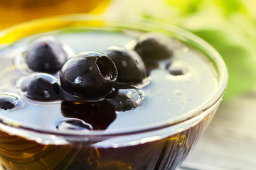 Fresh tasty beautiful black olives with olive oil on bowl on bright background.