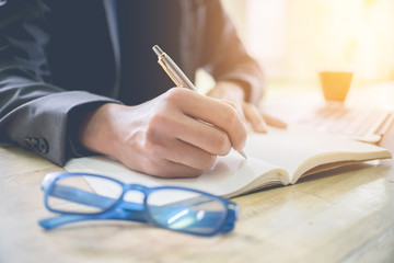 Business man writing on notebook at workplace. Vintage tone