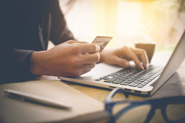 Online payment,Man's hands holding a credit card and using laptop computer for online shopping with vintage filter tone