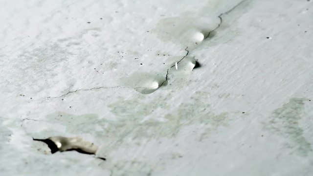 Water drips from ceiling. Faulty water supply in high-rise building. Cracked plaster on the ceiling.