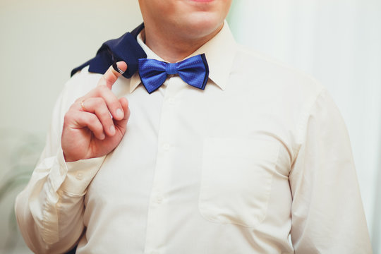 The young groom at the wedding holds the jacket with his hand