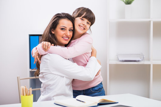 Female Doctor And Child Embracing At The Medical Office.