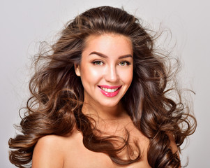 Naklejka premium Gorgeous Hair. Beauty Fashion Model Woman with Long and Healthy Brown Hair. Brunette Girl with long curly hair smiling. Professional Makeup.