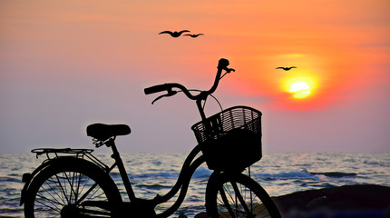 Silhouette of bicycle and sunset sky with clouds Sun on water texture with ripples along seashore summer beach at yellow evening horizon sea yellow sunset heaven background Outdoor