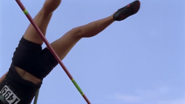 Girl pole vaulting in slow motion, seen from below bar
