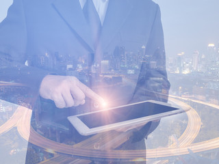 Double exposure of businessman using tablet with blur city background at night