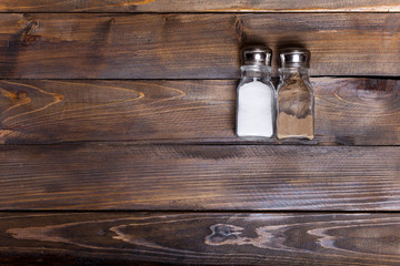 Two transparent cans of salt and pepper shaker on wooden background