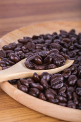 Coffee beans on a wooden spoon and plate on table