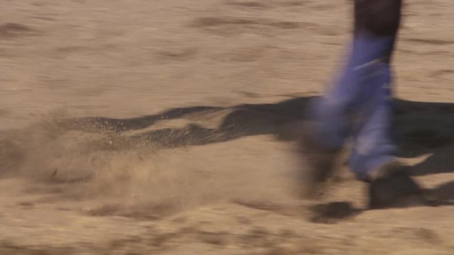 Close-up legs of a horse walking a tight circle in rodeo arena sand