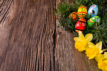 Wooden background with Easter eggs and daffodils.