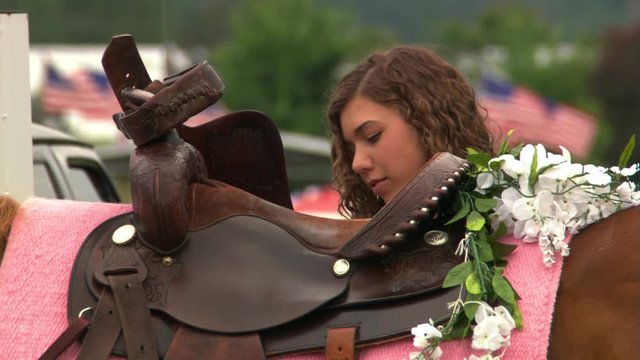 Close view of saddle decorated with flowers and face of young woman preparing to mount