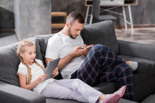 Father and daughter using digital devices