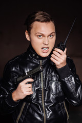 Man with black pistol and portable radio transceiver for communication.