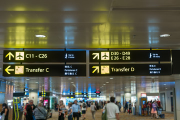 Yellow information sign at airport with gate number for departure and transfer flights in terminal...