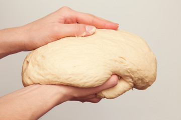 Hands holding a dough. It is ready for baking. Homemade pastries in the kitchen. Healthy eating lifestyle.
