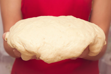 Hands holding a dough. It is ready for baking. Homemade pastries in the kitchen. Healthy eating lifestyle.