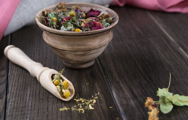 Herbal tea, herbs and flowers in a  clay cup on wooden table