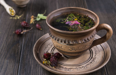 Hot cup of autumn tea with hip roses, chamomile, herbs on wooden table